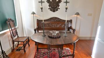 A dining area with a round wooden table, two chairs, a patterned rug, and wall-mounted candle holders.