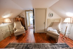 A room with two armchairs, a small table, a cabinet, and a door leading to another room.