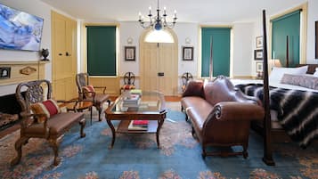 Une chambre traditionnelle avec un canapé, des fauteuils, une table basse, un lit et un téléviseur.