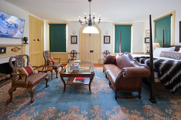 A traditional room with a sofa, chairs, a coffee table, a bed, and a television.