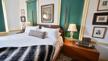 A hotel room with a large bed, a wooden nightstand, a mirror, and framed pictures on the wall.