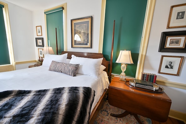 A hotel room with a large bed, a wooden nightstand, a mirror, and framed pictures on the wall.
