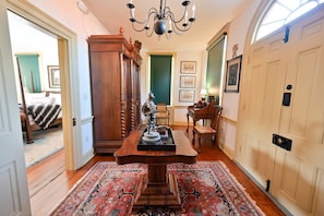 A traditional room with a wooden dining table, two rugs, a chandelier, and a green door.