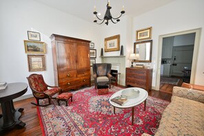 Una habitación con un gran armario de madera, un sillón de cuero, una mesa redonda de centro y un tapete estampado.