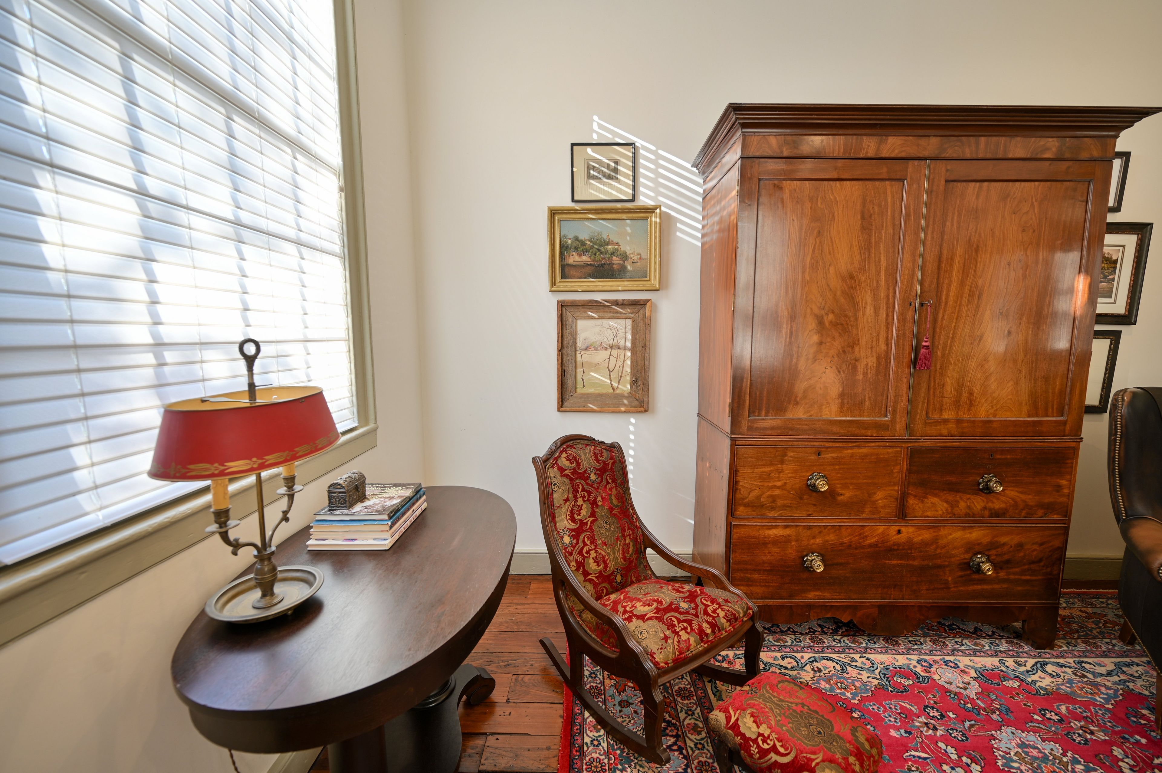 A room with a wooden desk, a chair, a cabinet, and a window with blinds.