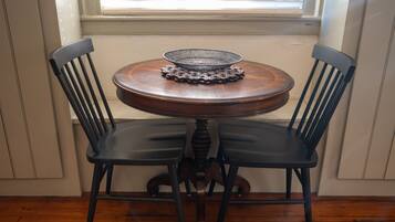 A round wooden table with a metal tray and two black chairs with wooden legs.