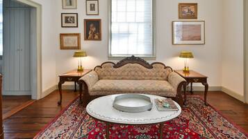 A room with a sofa, two lamps, a patterned rug, and framed pictures on the wall.