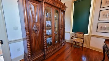 Een kamer met een houten kast, een stoel en wanddecoraties in lijsten.