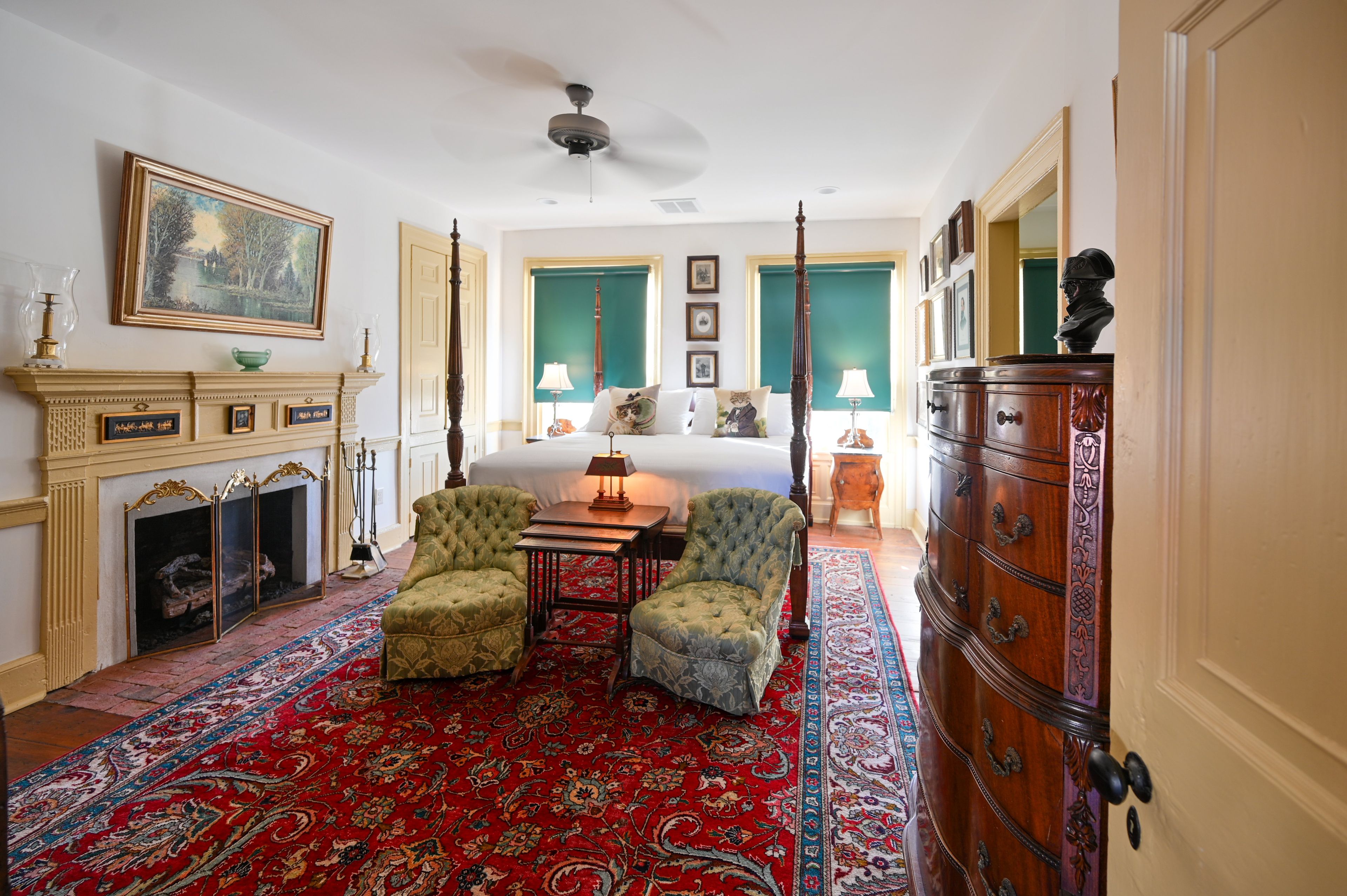 A traditional room with a fireplace, a four-poster bed, and a large wooden dresser.