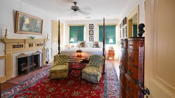A traditional room with a fireplace, a four-poster bed, and a large wooden dresser.