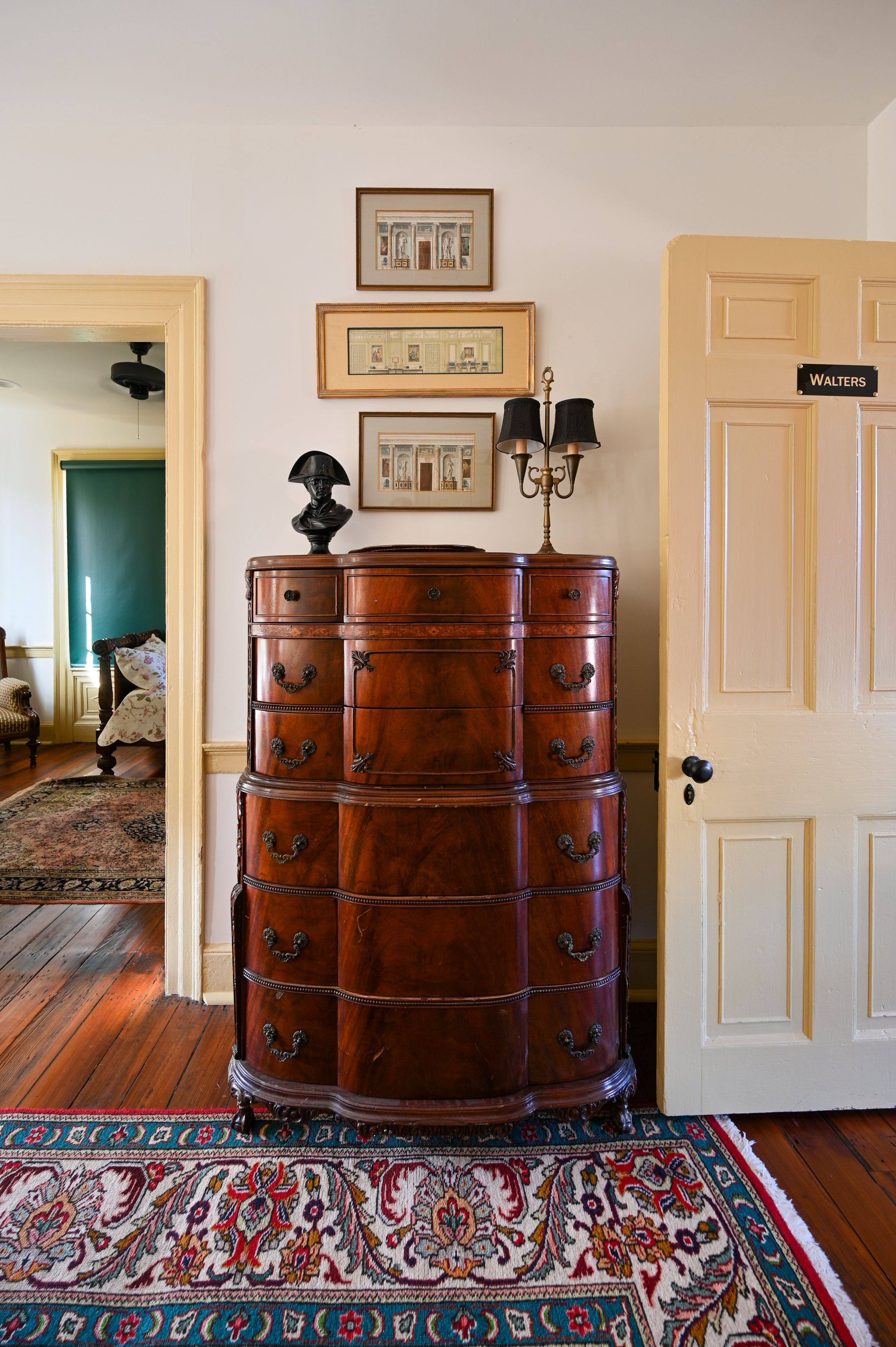 A room with a large wooden chest of drawers, a chandelier, and a door labeled 'WALTERS'.