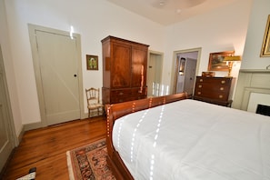 Ein Schlafzimmer mit einem großen Bett, einem Holzschrank und einem Stuhl.