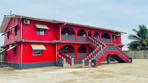 A two-story building with a red facade, multiple windows, and a staircase leading to an upper level.