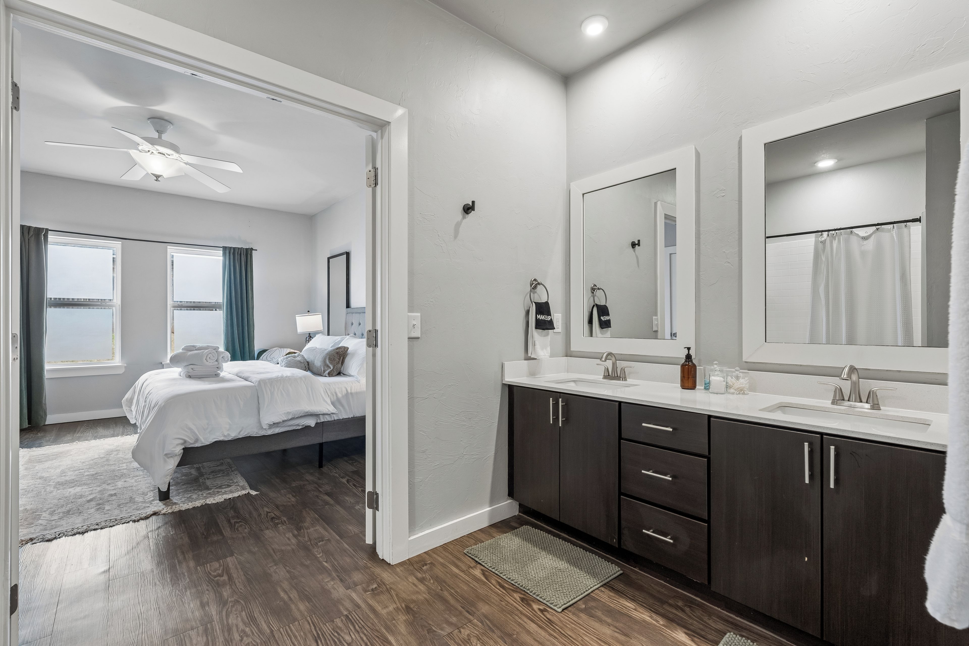 A modern bathroom with a large mirror, dark cabinets, and a white sink.