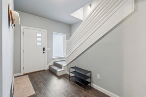 A hallway with a white door, a window, a staircase, and a small shelf. - Spacious 5-bedroom house perfect for groups (Edmond)