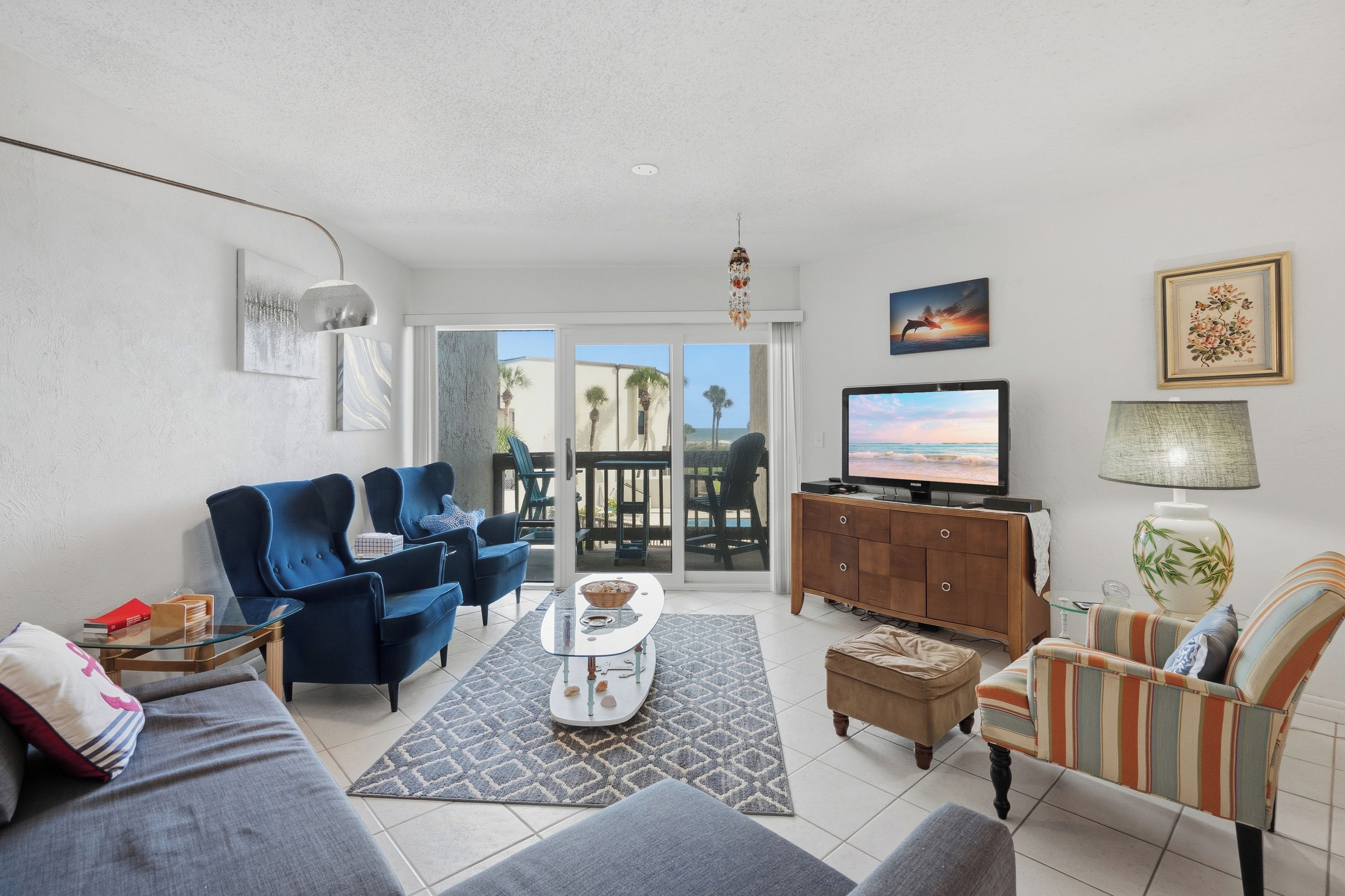 A living room with a sofa, armchairs, a coffee table, a TV, and a cabinet.