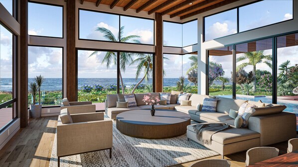 Ampla sala de estar com grande janela vista para piscina e oceano, mobiliada com sofás e mesa de centro.