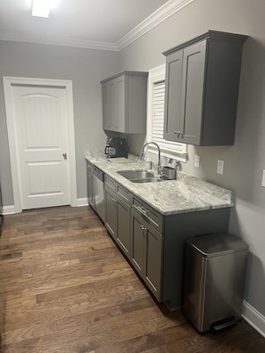 A kitchen with a marble countertop, stainless steel appliances, and a trash can. - The Grove Getaway Standalone Townhome 4BR/4.5BA Near Ole Miss (Oxford)