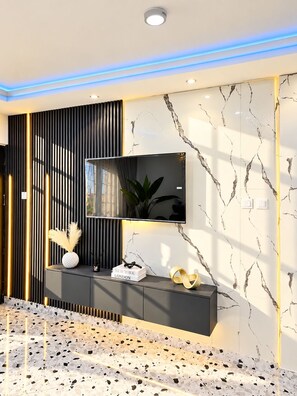 A modern interior with a marble wall, a black and gold console, a flat-screen TV, and a terrazzo floor. - Afro Coastal Villa  Modern 3-Bedroom En-Suite Retreat Near the Sea in Accra (Accra)