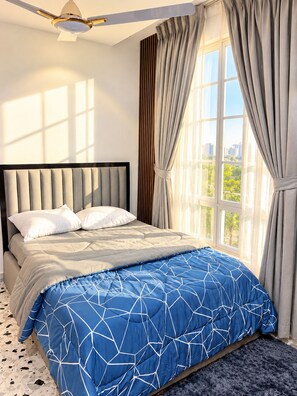 A bedroom with a bed, a ceiling fan, a window with curtains, and a view of greenery outside. - Afro Coastal Villa  Modern 3-Bedroom En-Suite Retreat Near the Sea in Accra (Accra)
