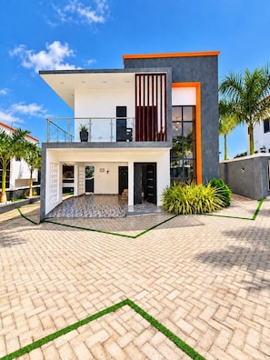 A modern two-story house with a balcony, a paved courtyard, and a well-maintained garden. - Afro Coastal Villa  Modern 3-Bedroom En-Suite Retreat Near the Sea in Accra (Accra)