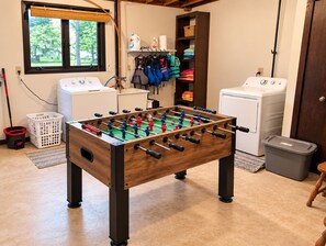 Ein Zimmer mit Kicker, Waschmaschine, Trockner und Wäschekorb.