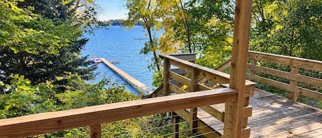 Une terrasse en bois offrant une vue sur un lac, entourée d’arbres.