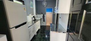A narrow kitchen with a refrigerator, a coffee maker, and a microwave. - Karon Homes (Karon)