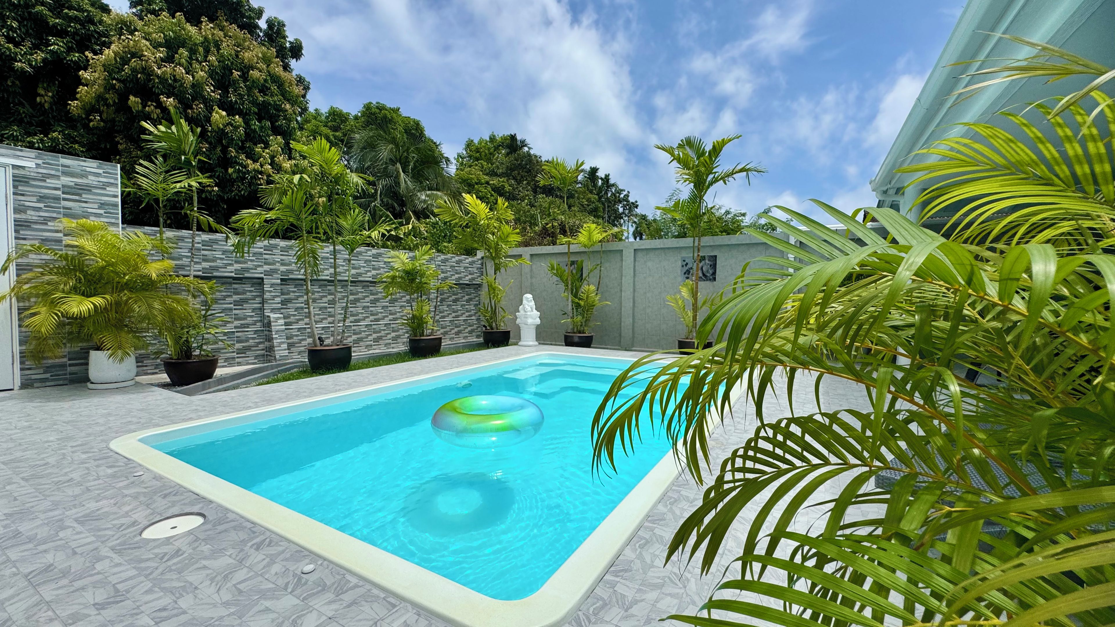 Una piscina rectangular con superficie de agua azul cristalina, rodeada por una solana con baldosas.