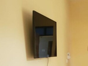Een aan de muur bevestigde televisie met een zichtbare stekkerdoos aan de rechterkant.