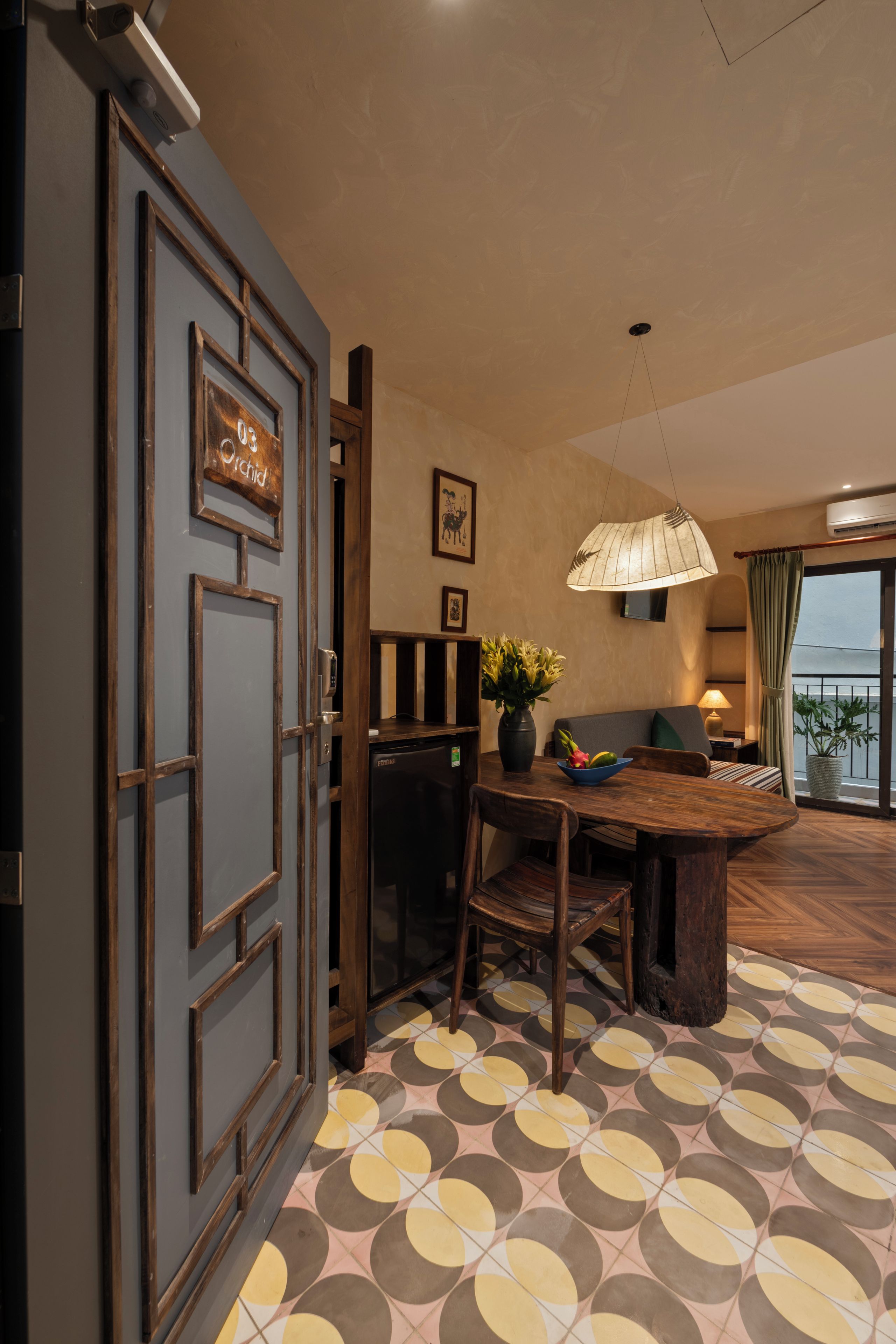 Habitación de hotel con zona de comedor, un amplio ventanal con vistas y suelo estampado.