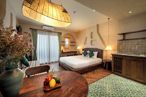 A hotel room with a bed, a dining table with fruits, a kitchen area, and a large window with curtains. - Tranquility Suites Westlake (Hanoi)