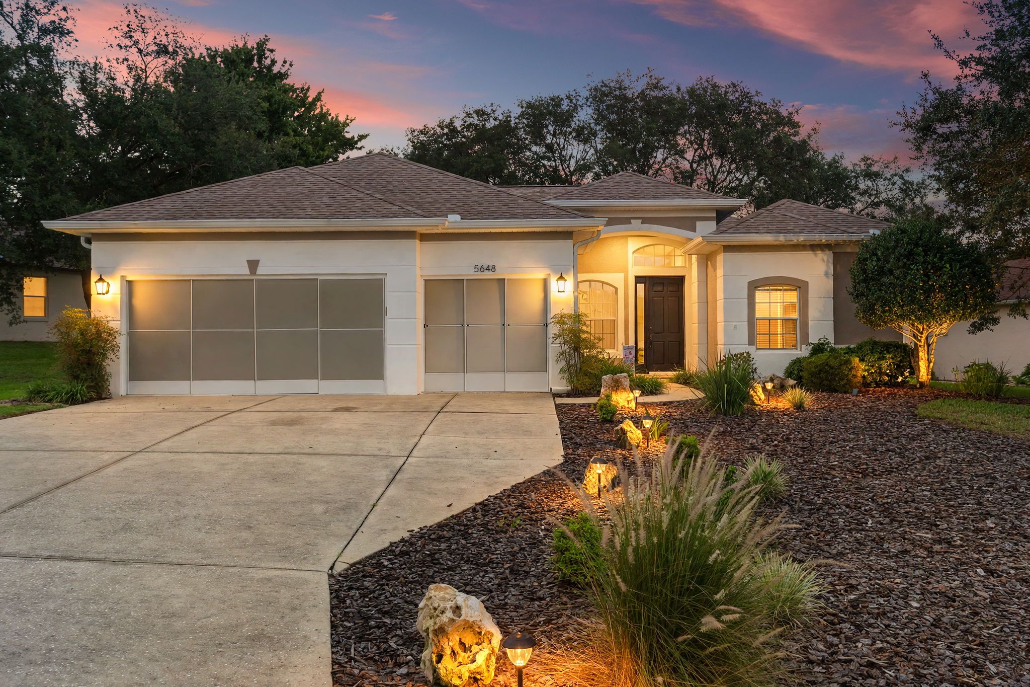 A two-story house with a garage, driveway, and landscaped garden.