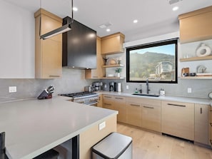 A modern kitchen with a large window, built-in cabinets, and a stainless steel stove. - Ski-In 5BR Canyons Village | Hot Tub + Fire Pit | Steps to Gondola (Park City)