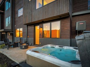 A modern building with a hot tub, outdoor seating, and a chimney. - Ski-In 5BR Canyons Village | Hot Tub + Fire Pit | Steps to Gondola (Park City)