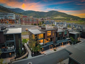 A modern hotel complex with multiple buildings, a parking lot, and a view of mountains in the background. - Ski-In 5BR Canyons Village | Hot Tub + Fire Pit | Steps to Gondola (Park City)