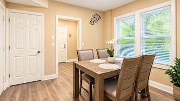 A dining area with a wooden table, chairs, and a vase with flowers.