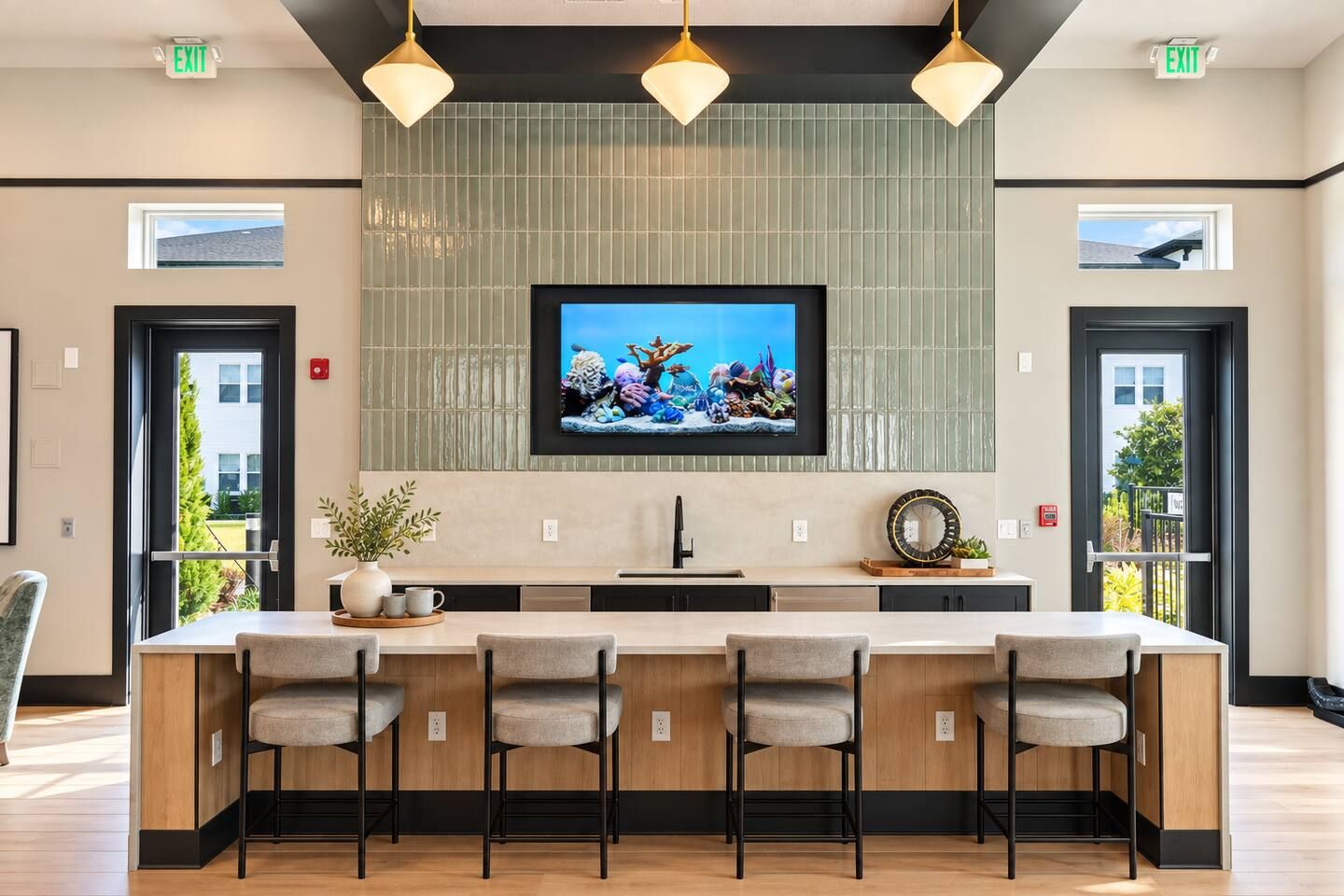 Une cuisine moderne dotée d’un grand îlot central, de tabourets de bar, de luminaires suspendus et d’un téléviseur fixé au-dessus de l’îlot.