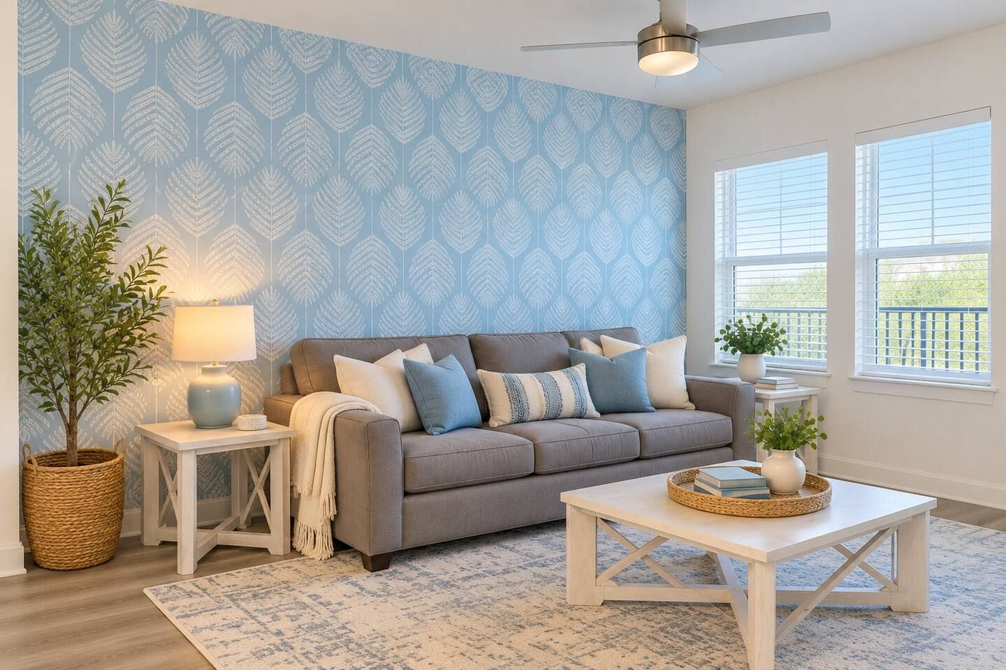 Un salon avec un canapé gris, une table basse blanche, un mur à motifs et un ventilateur de plafond.