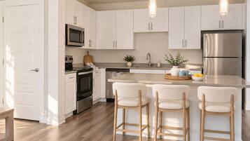 A modern kitchen with white cabinets, stainless steel appliances, and a central island with bar stools.