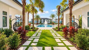 A pool area with a clear view of the pool, surrounded by palm trees and a well-maintained lawn.