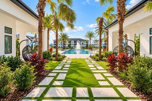 A pool area with a clear view of the pool, surrounded by palm trees and a well-maintained lawn. - 1BR King Suite - Pool, Gym, Games & Dog Friendly (Middleburg)