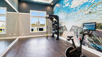 Une salle de sport moderne dotée d’un grand miroir, d’appareils d’exercice et d’une fresque murale représentant un paysage.