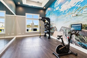 A modern gym with a large mirror, exercise equipment, and a scenic mural. - 1BR King Suite - Pool, Gym, Games & Dog Friendly (Middleburg)