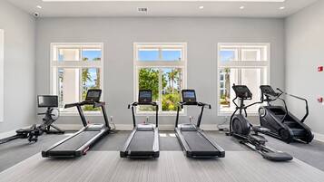Une salle de sport équipée de trois tapis de course, d’un vélo elliptique et d’un vélo d’appartement, tous dotés d’écrans numériques.