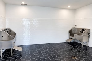 A restroom with two sinks, white tiled walls, and a black hexagonal floor. - 2BR Suite - Pool, Gym, Games & Dog Friendly (Middleburg)