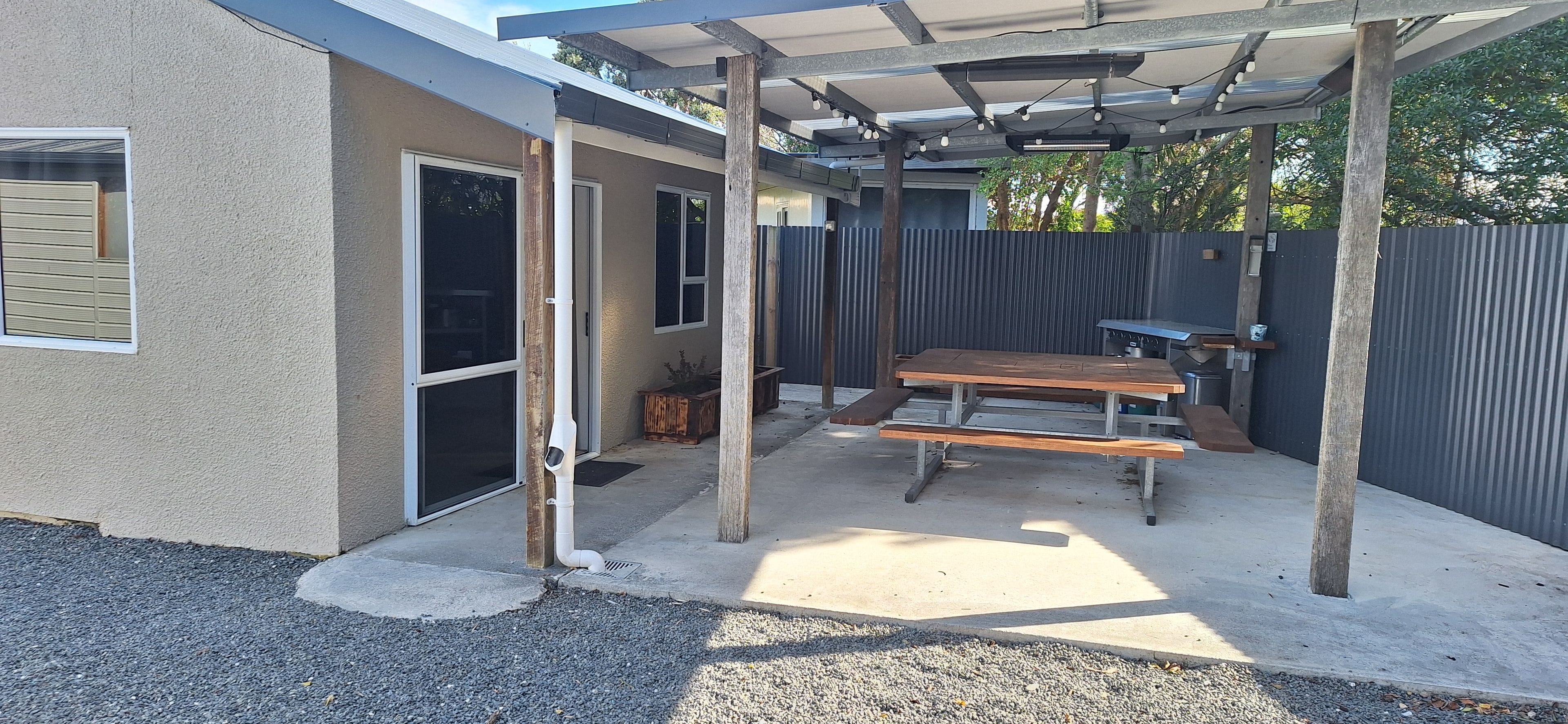 Un espace extérieur aménagé en terrasse, avec une table de pique-nique et une structure en forme de pergola.