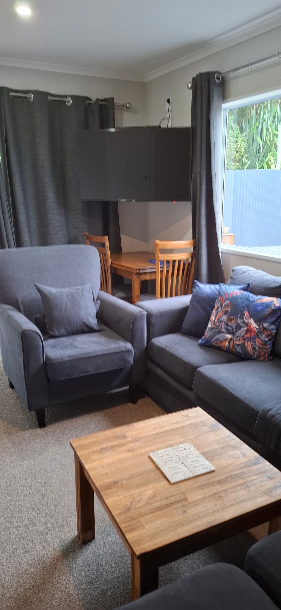 A modern living room with a grey sofa, a wooden coffee table, and a television mounted on the wall.