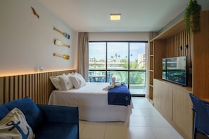 Quarto de hotel com cama, televisão, varanda e um sofá azul.