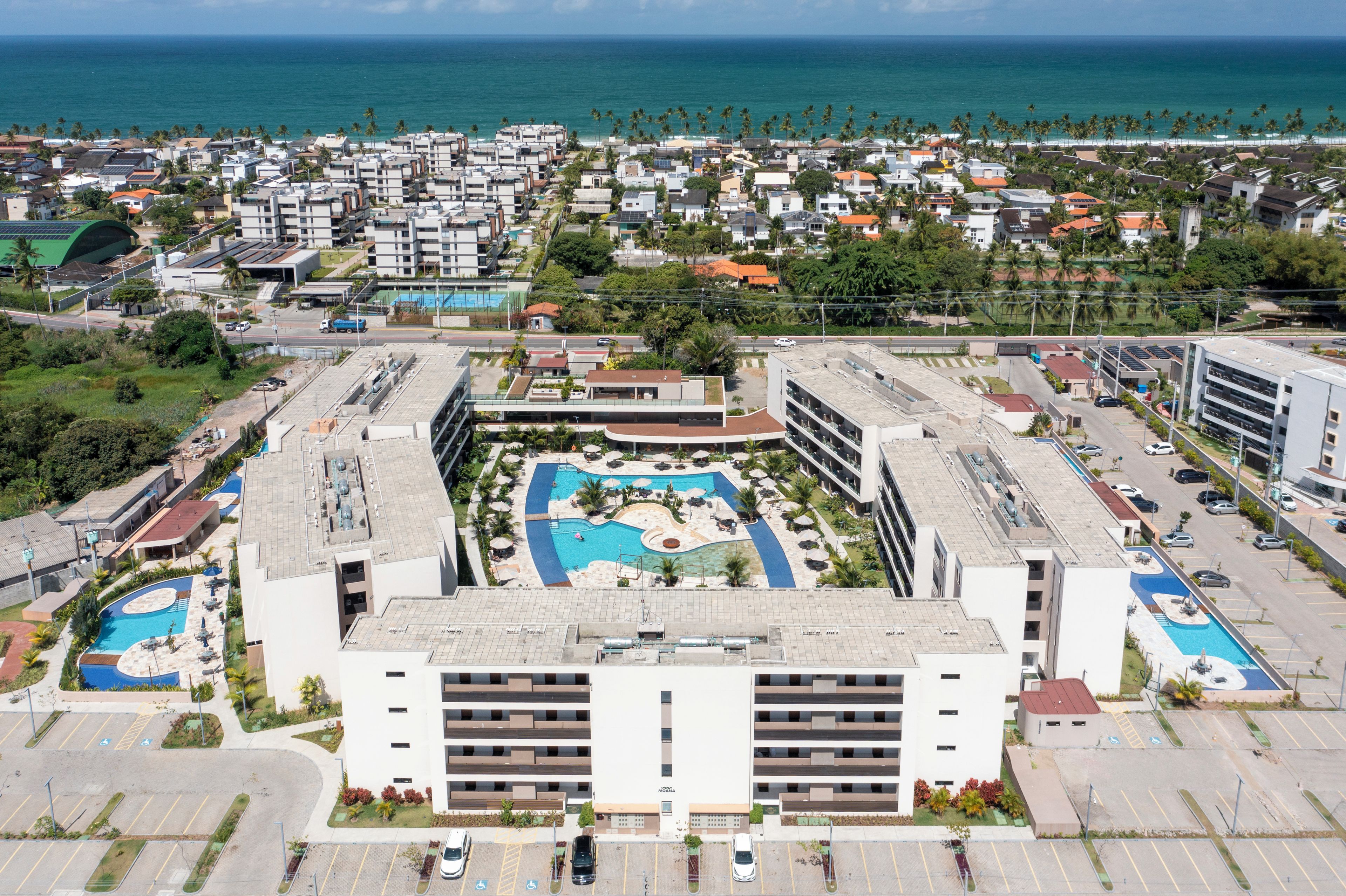 Un hotel con piscina en la azotea, varios niveles de estacionamiento y vistas al océano.